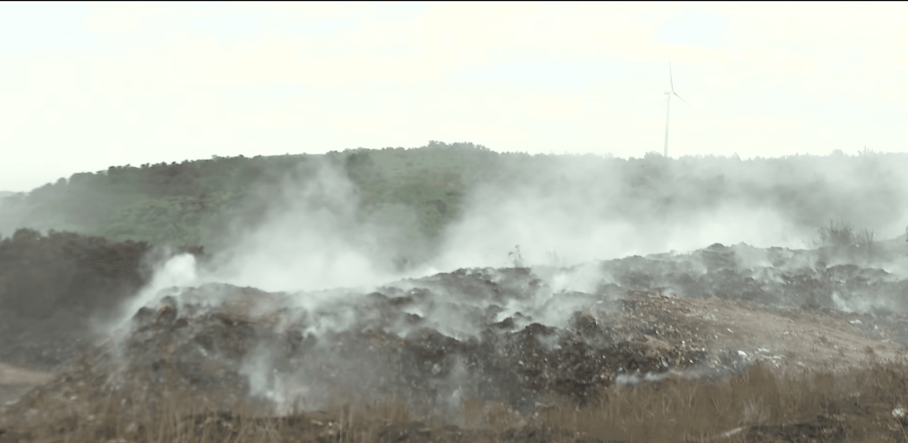 Illustrative photograph of smoke rising over piles of waste.